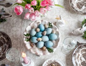Patera z jajkami pofarbowanymi na niebiesko czerwoną kapustą stoi na stole.